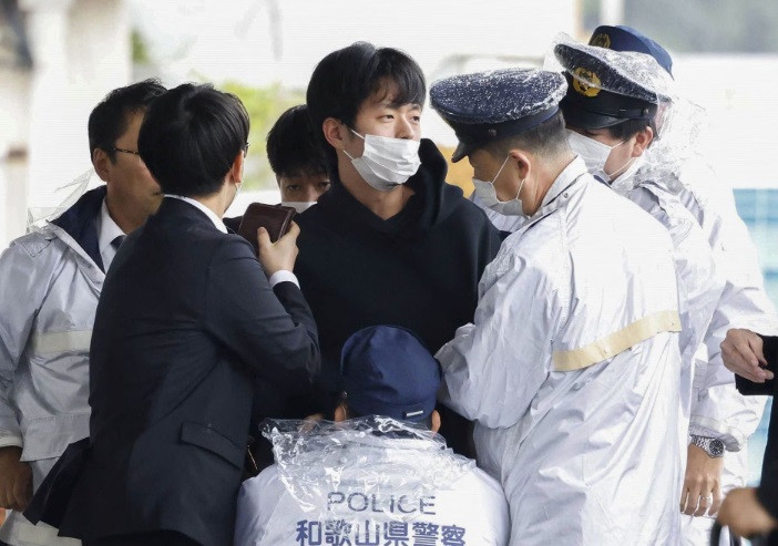 a man believed to be a suspect who threw a pipe like object near japanese prime minister fumio kishida during his outdoor speech is held by police officers at saikazaki fishing port in wakayama wakayama prefecture south western japan april 15 2023 in this photo released by kyodo mandatory credit kyodo via reuters