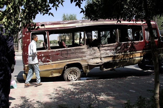 A boy walks past the wreckage of a bus following a suicide bombing in Kabul. PHOTO: AFP