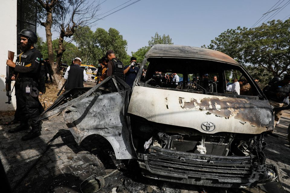 police officers and members of the investigation team gather near a passenger van after a blast at the entrance of the confucius institute university of karachi photo reuters