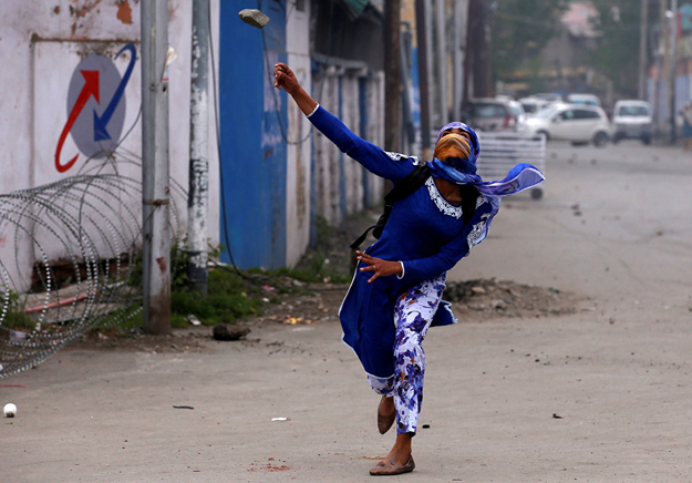 A Kashmiri student throws a stone at Indian police during a protest in Srinagar on April 24, 2017. Female students from various colleges in IOK took part in mass protests against Indian soldiers. PHOTO: REUTERS