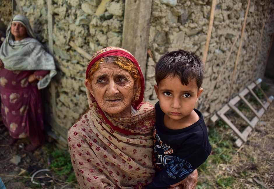 A Kashmiri woman holds a child as she looks on outside her a damaged house following recently cross border shelling at the Line of Control, the de facto border between Pakistan and India, in Neelum Valley of Pakistan-administered Kashmir. PHOTO: AFP