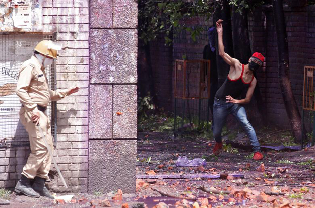 A Kashmiri student throws a piece of brick towards Indian policemen during a protest in Srinagar. PHOTO: REUTERS