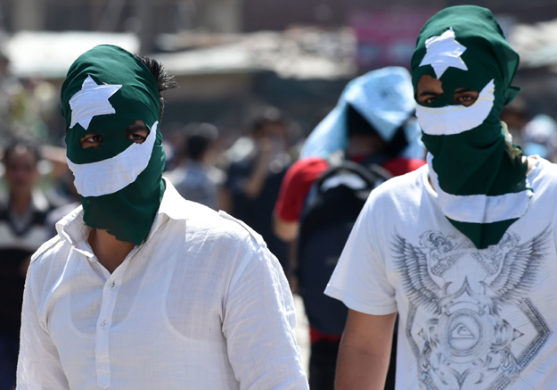 Kashmiri protestors, their faces masked with Pakistani flags, look towards Indian government forces during clashes after Friday congregational prayers outside The Jamia Masjid in Srinagar on May 5, 2017. PHOTO: AFP