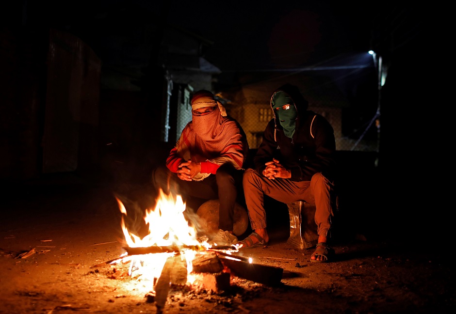 Kashmiri men, on the night time doing guard duty, warm themselves at a barricade to prevent Indian security forces from entering Anchar neighbourhood. PHOTO: REUTERS