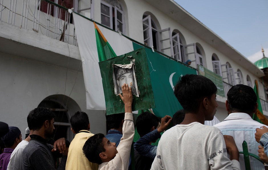 A Kashmiri boy touches the photo of Burhan Wani, a dead militant commander, as others participate in a protest at Jinab Sahib mosque. PHOTO: REUTERS