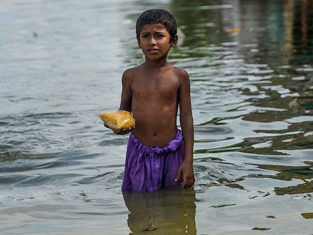 a boy wades through a flooded street in karachi photo afp