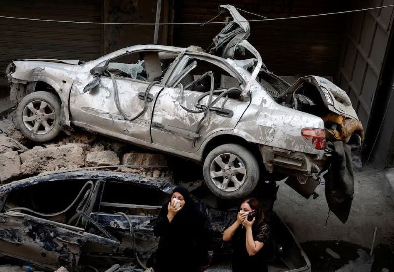 women stand next to damaged vehicles at the site of an israeli air strike amid ongoing hostilities between hezbollah and israeli forces in beirut lebanon october 11 2024 photo reuters