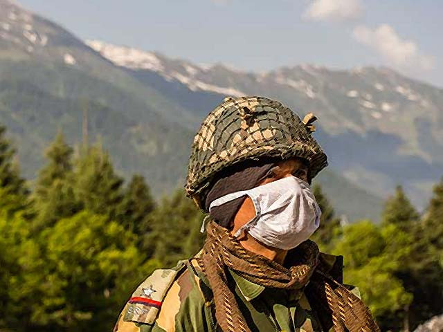 an indian border security force soldier guards a highway as an indian army convoy makes way towards leh bordering china photo afp