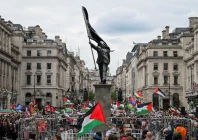 people hold palestinian flags next to a statue depicting a figure carrying a flag covering their face and stepping off a plinth by british street artist banksy during a march held by palestine solidarity campaign to mark the 78th anniversary of the nakba and against the unite the kingdom rally taking place in london organised by british anti immigration activist stephen yaxley lennon also known as tommy robinson in london britain may 16 2026 reuters