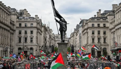 people hold palestinian flags next to a statue depicting a figure carrying a flag covering their face and stepping off a plinth by british street artist banksy during a march held by palestine solidarity campaign to mark the 78th anniversary of the nakba and against the unite the kingdom rally taking place in london organised by british anti immigration activist stephen yaxley lennon also known as tommy robinson in london britain may 16 2026 reuters