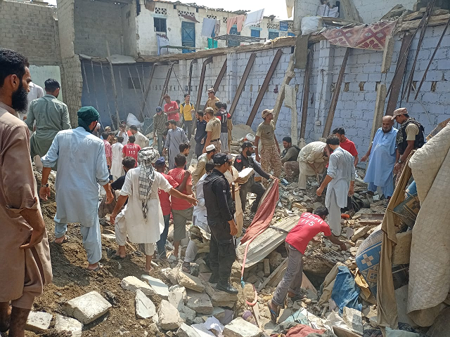 rescue officials and onlookers gather around the building that collapsed in lyari photo express