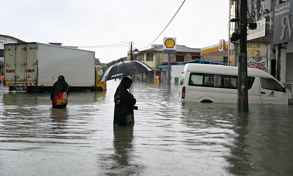 a woman looks at a submerged vehicle during heavy rain in pasir puteh in malaysia s kelantan state on november 30 2024 photo afp