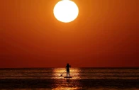 a woman looks at the sunrise as she paddleboards on the mediterranean sea in barcelona spain july 2 2025 photo reuters