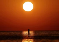 a woman looks at the sunrise as she paddleboards on the mediterranean sea in barcelona spain july 2 2025 photo reuters