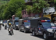 commuters ride past security personnel as they patrol a street ahead of a protest by the banned jaac in muzaffarabad capital of azad jammu and kashmir on june 7 2026 photo afp