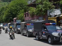 commuters ride past security personnel as they patrol a street ahead of a protest by the banned jaac in muzaffarabad capital of azad jammu and kashmir on june 7 2026 photo afp