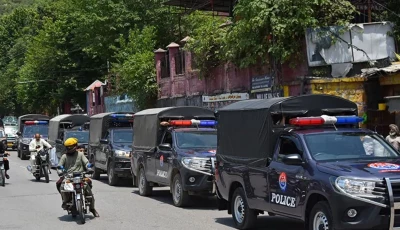 commuters ride past security personnel as they patrol a street ahead of a protest by the banned jaac in muzaffarabad capital of azad jammu and kashmir on june 7 2026 photo afp