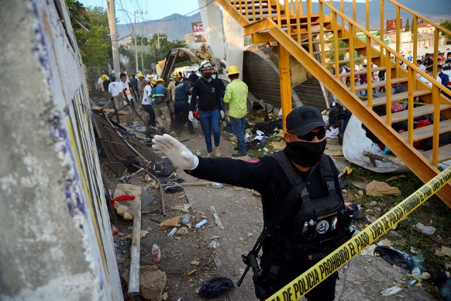 a police officer raises his arm to block photographers to to avoid taking pictures at the site of a trailer accident that left at least 49 people dead most of them migrants from central america in tuxtla gutierrez in chiapas state mexico december 9 2021 reuters jacob garcia