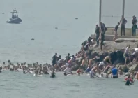 by sea migrants swim through spain s ceuta border from the moroccan side and climb onto rocks to reach the border fence in ceuta spain photo reuters