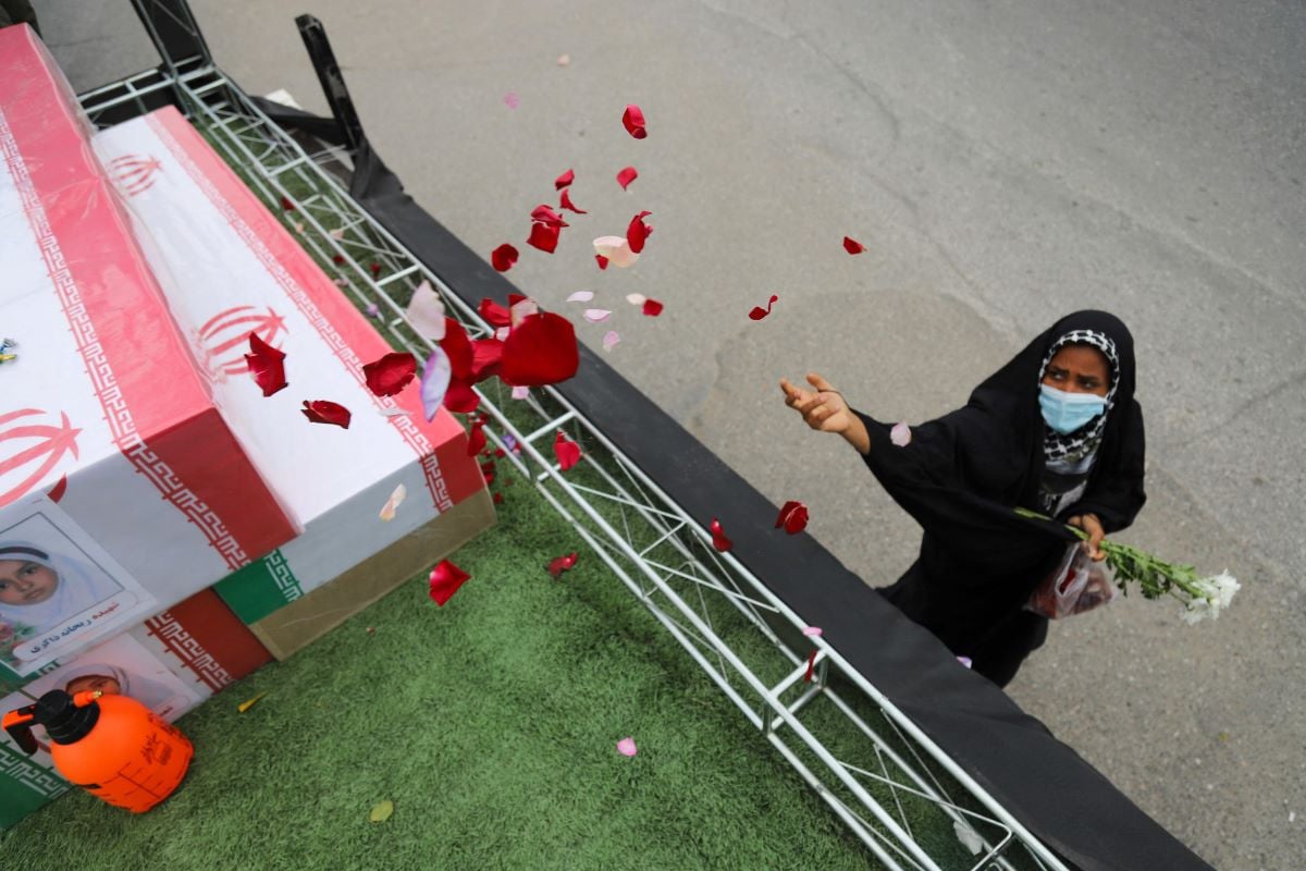 A mourner sprays flower petals on the coffins of children who were killed in a reported strike on a primary school in Iran s Hormozgan province during a funeral in Minab on March 3, 2026. PHOTO: ISNA/Reuters