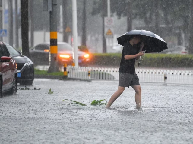a man braves the rain as he makes his way through a flooded section of the road amid heavy rainfall brought by typhoon matmo in haikou hainan province china october 5 2025 photo reuters