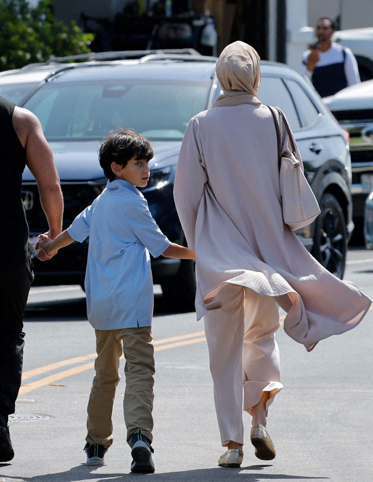 child holds his parents hands as they leave the mosque, at the scene of a shooting at the Islamic Center in San Diego, California, US, May 18, 2026.  REUTERS