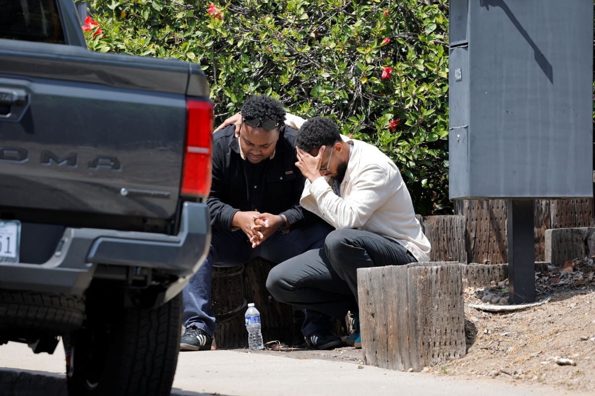 Men console each other as they sit on a sidewalk, near the scene of a reported active shooter situation at the Islamic Center, in San Diego, California, US, May 18, 2026.  REUTERS
