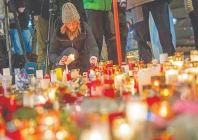 a mourner lights a candle at a makeshift memorial near the site of a fire that ripped through a bar during new year s eve celebrations in the alpine ski resort town of crans montana photo afp