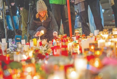 a mourner lights a candle at a makeshift memorial near the site of a fire that ripped through a bar during new year s eve celebrations in the alpine ski resort town of crans montana photo afp