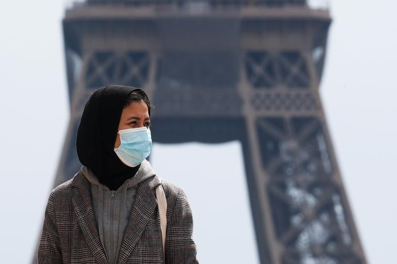 a woman wearing a hijab and a protective face mask walks at trocadero square near the eiffel tower in paris france may 2 2021 picture taken on may 2 2021 photo reuters