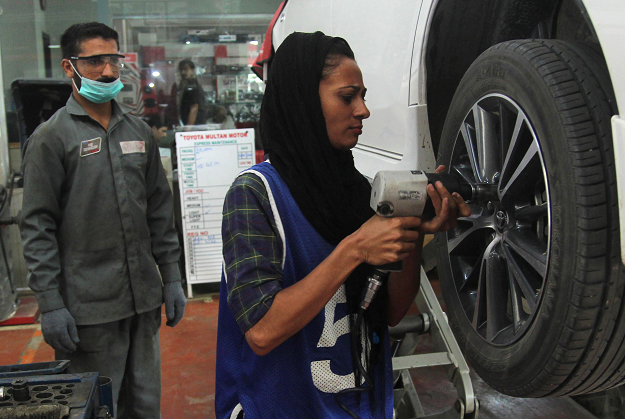 Nawaz, 24, fixes a car at an auto workshop in Multan. PHOTO: AFP