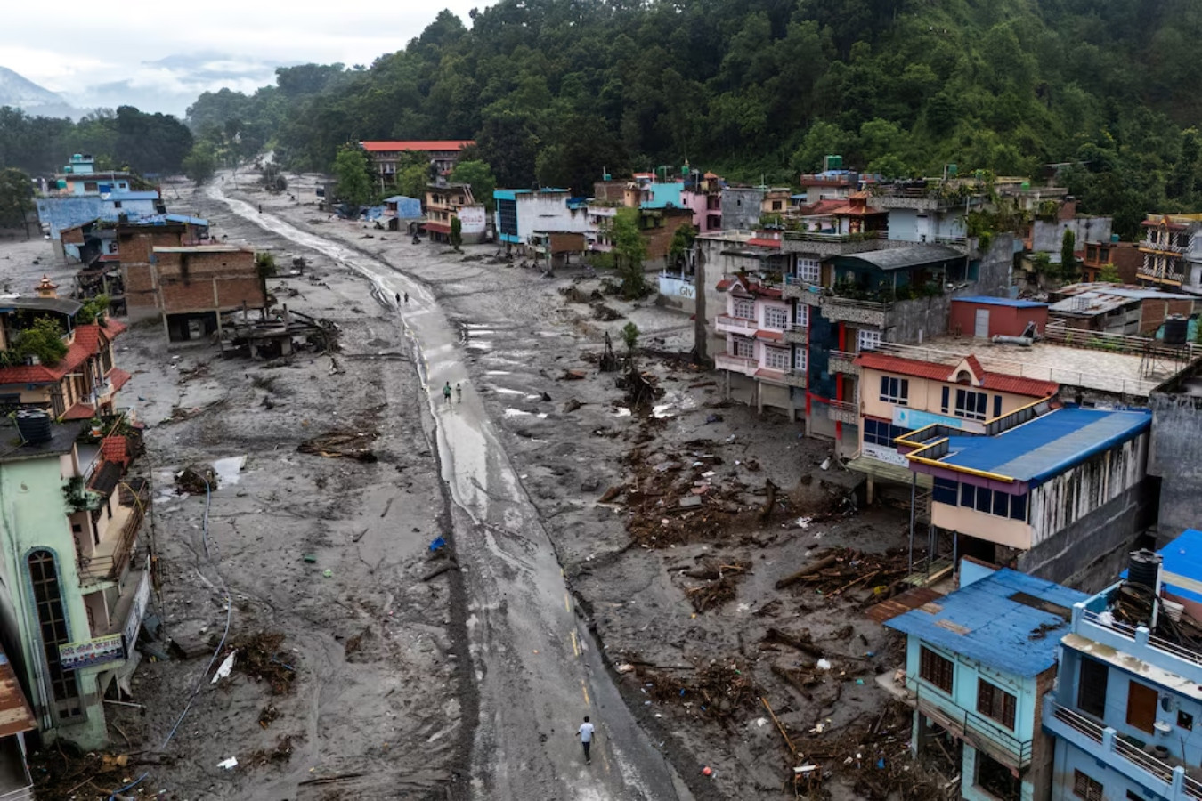 A drone view shows people walk on a road and houses covered in mud following deadly flash floods and mudslides, in Devighat, Nuwakot district, Nepal, August 30, 2026. REUTERS