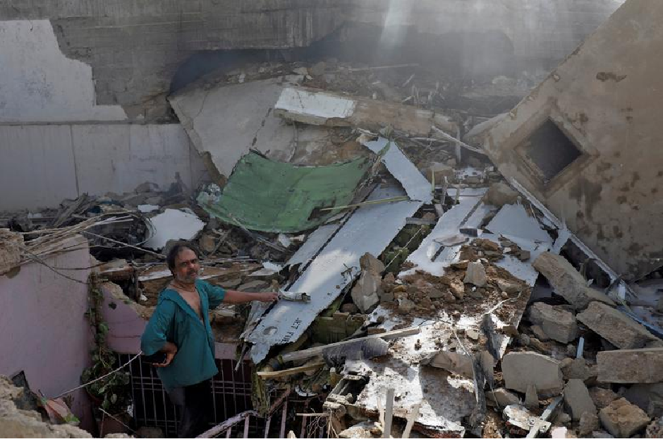 A man stands on the debris of a house at the site of a passenger plane crash in a residential area near an airport in Karachi. PHOTO: REUTERS