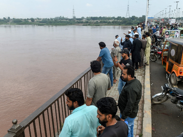 Commuters watch the Ravi River from a bridge as the government announced a flood alert in the riverside areas of Punjab province, in Lahore on August 27, 2025. Photo: AFP