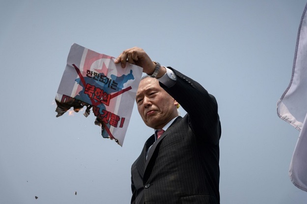 An anti-North Korea activist burns a North Korean flag placard during a demonstration in Seoul. PHOTO: AFP