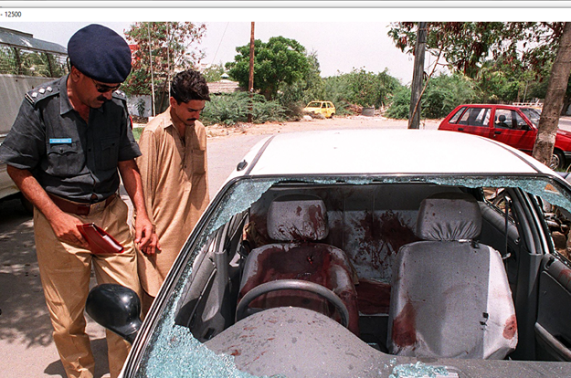  In this file photo taken on July 5, 1997, a police officer inspects the bullet-riddled car of Shahid Hamid, managing director of the state-run Karachi Electric Supply Corporation (KESC), who was killed along with his driver and guard by unidentidied gunmen in Karachi