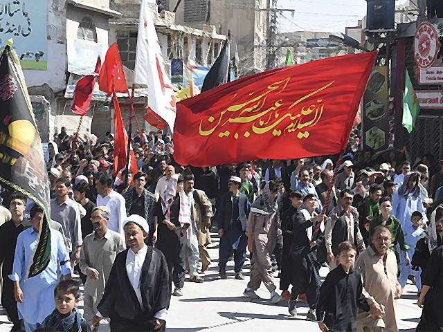 shiite muslims hold religious flags as they march in quetta photo afp