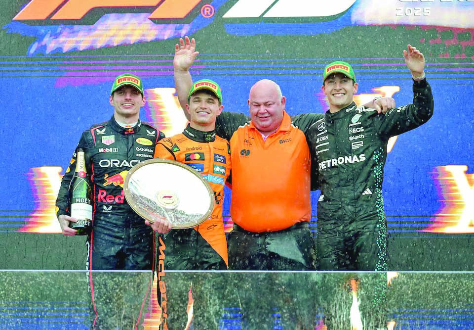 mclaren s lando norris celebrates with the trophy on the podium after winning the australian grand prix along with second placed red bull s max verstappen and third placed mercedes george russell at albert park grand prix circuit melbourne photo reuters