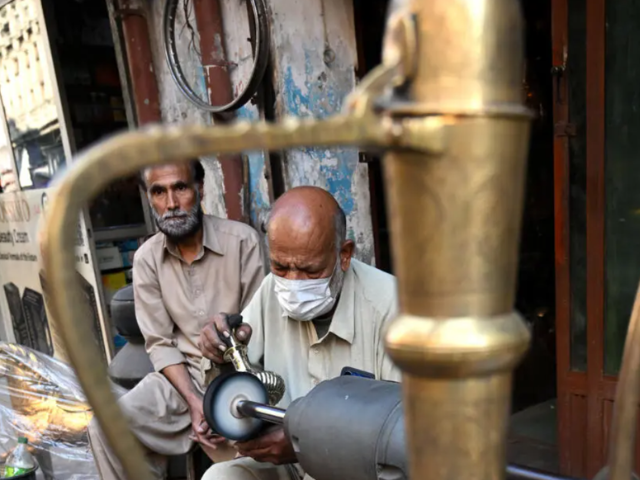 Antique dealer Ahsan Shakeel polishes an artefact outside his shop selling vintage items in Rawalpindi. PHOTO: AFP