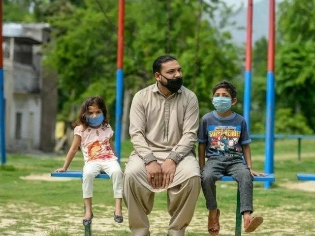 A Reuters image of a man with two children on a swing.