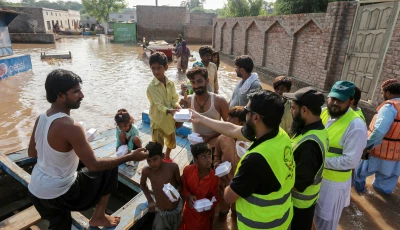 volunteers distribute food packets to villagers in flood affected areas as the sutlej river swelled following heavy rains on the outskirts of multan in punjab province on september 5 2025 photo afp