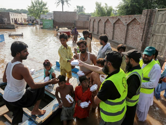 volunteers distribute food packets to villagers in flood affected areas as the sutlej river swelled following heavy rains on the outskirts of multan in punjab province on september 5 2025 photo afp