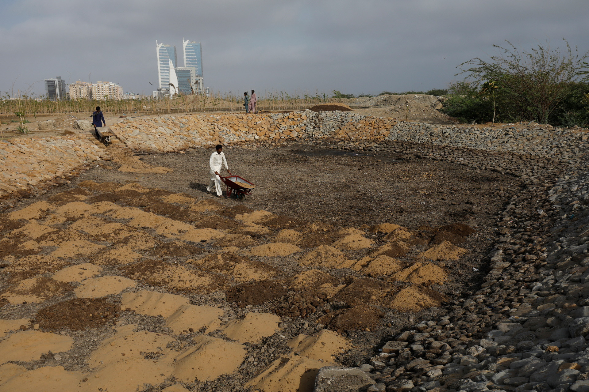 Workers prepare a pool with sand, molasses and soil which is going to be a part of the Clifton Urban Forest, May 26, 2021. REUTERS