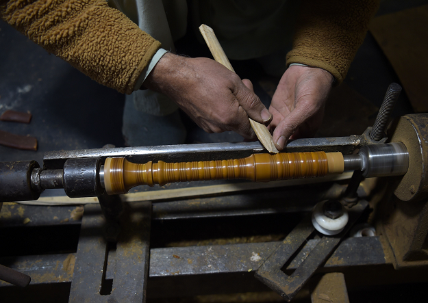 In this picture taken on January 25, 2019, Pakistani artisan works on a machine to make components to be used to make a set of bagpipes at the Mid East bagpipe factory in the eastern city of Sialkot. PHOTO: AFP