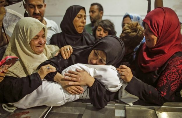 Mourners gather around as a mother holds her baby who died in the protests on May 15, 2018. PHOTO: AFP