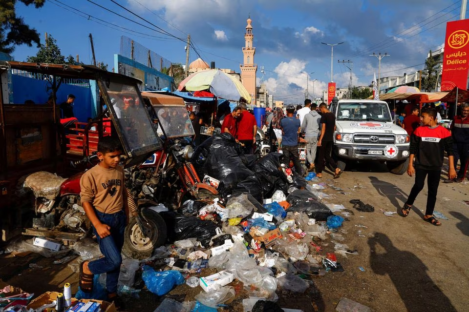 Palestinians walk past piles of garbage that threaten to spark an environmental catastrophe, amid the ongoing Israeli-Palestinian conflict, in Khan Younis in the southern Gaza Strip. PHOTO: REUTERS