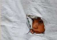 a displaced palestinian boy peers through a tear in a tent wall in gaza city may 6 2026 photo file reuters
