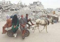 palestinians ride a donkey cart past piles of garbage and destroyed buildings in khan younis photo reuters