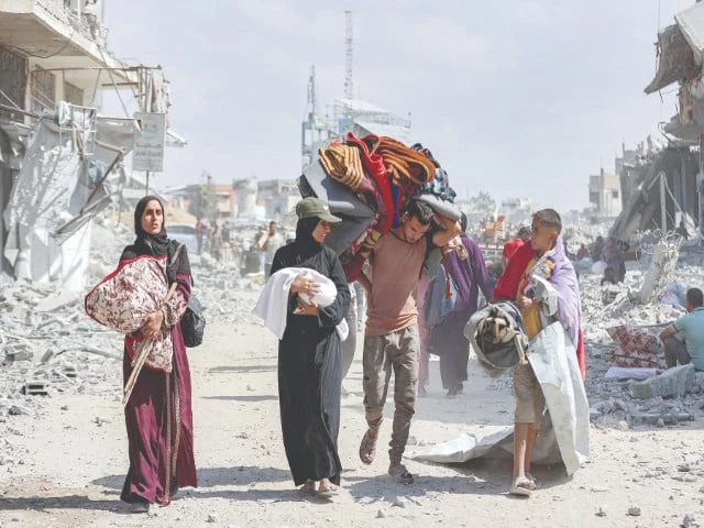 a woman carrying a child speaks with another boy as they walk with other people past the rubble of destroyed buildings in the centre of khan yunis in the southern gaza strip photo afp a woman carrying a child speaks with another boy as they walk with other people past the rubble of destroyed buildings in the centre of khan yunis in the southern gaza strip photo afp