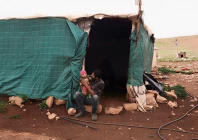 suhaib abu kbash sits with his child on his lap outside their makeshift house in a palestinian bedouin community in the jordan valley in the israeli occupied west bank march 19 2026 photo reuters